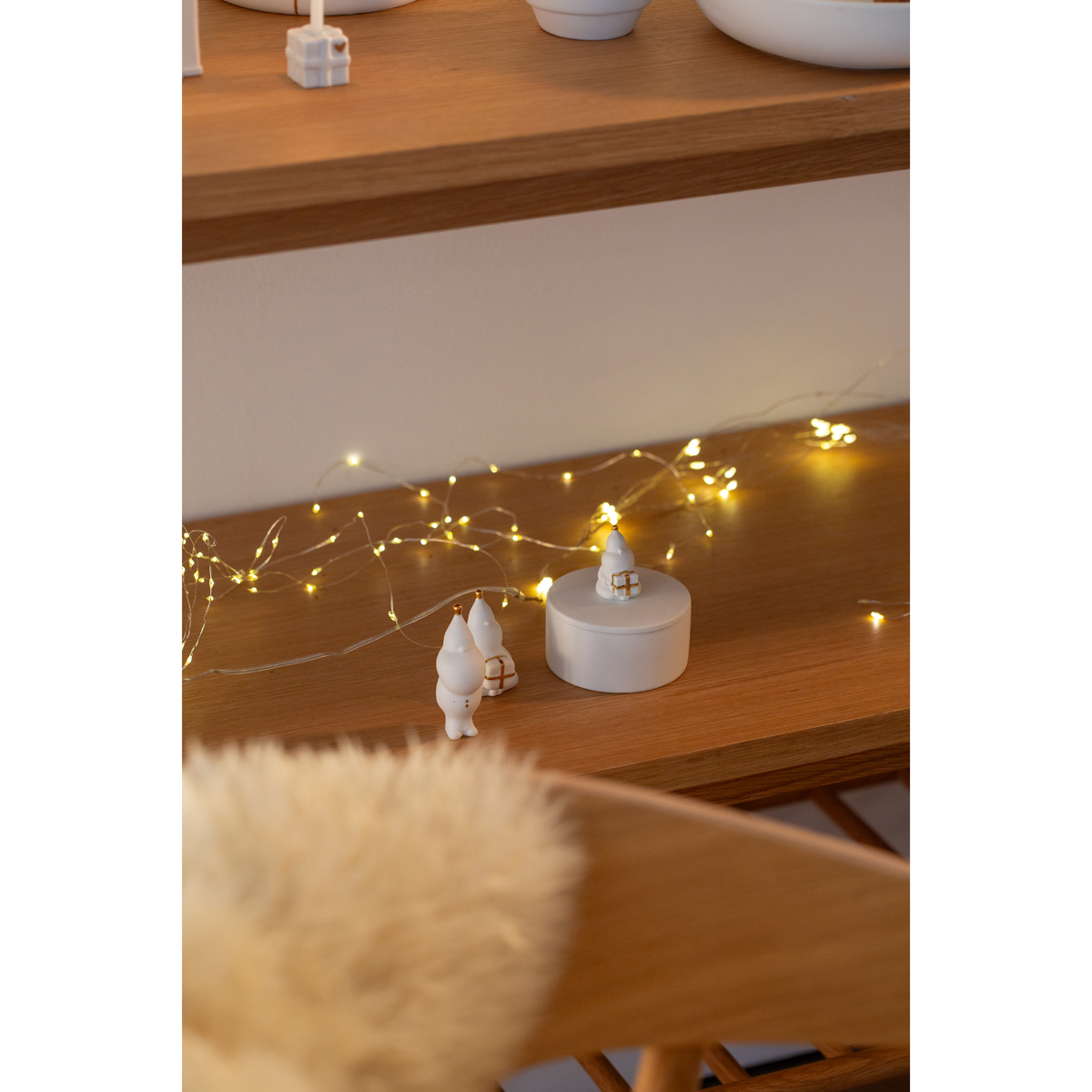 Dose Santa und Santa-Figuren dekoriert auf Anrichte mit Lichterkette und einenm kleinen Santa daneben