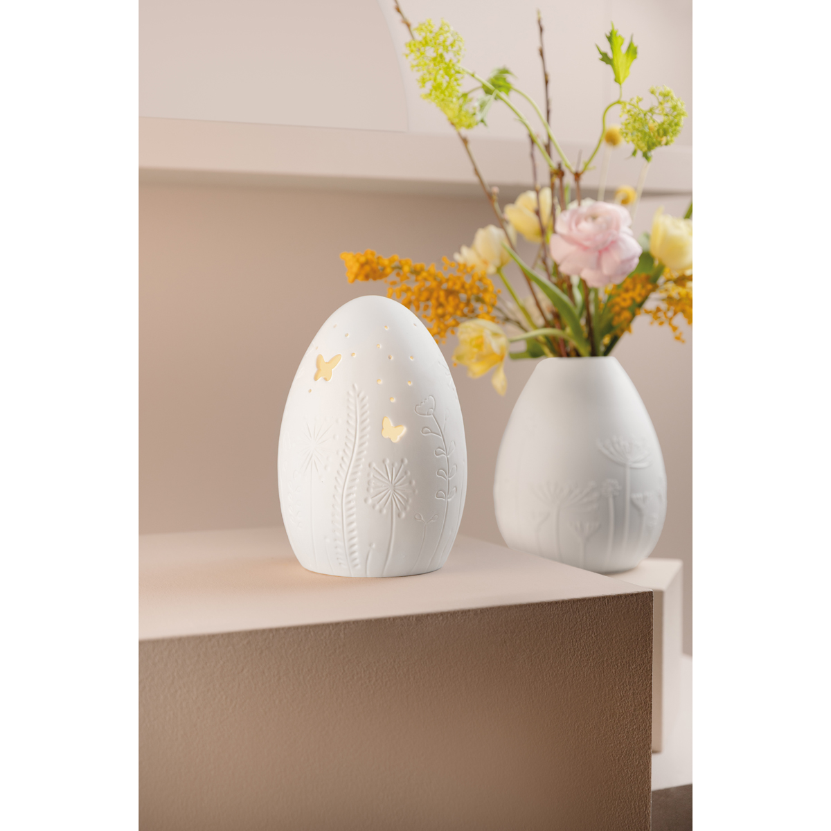 LED-Leuchte arrangiert mit einer Eivae und einem Frühlingsstrauss auf einem Tisch